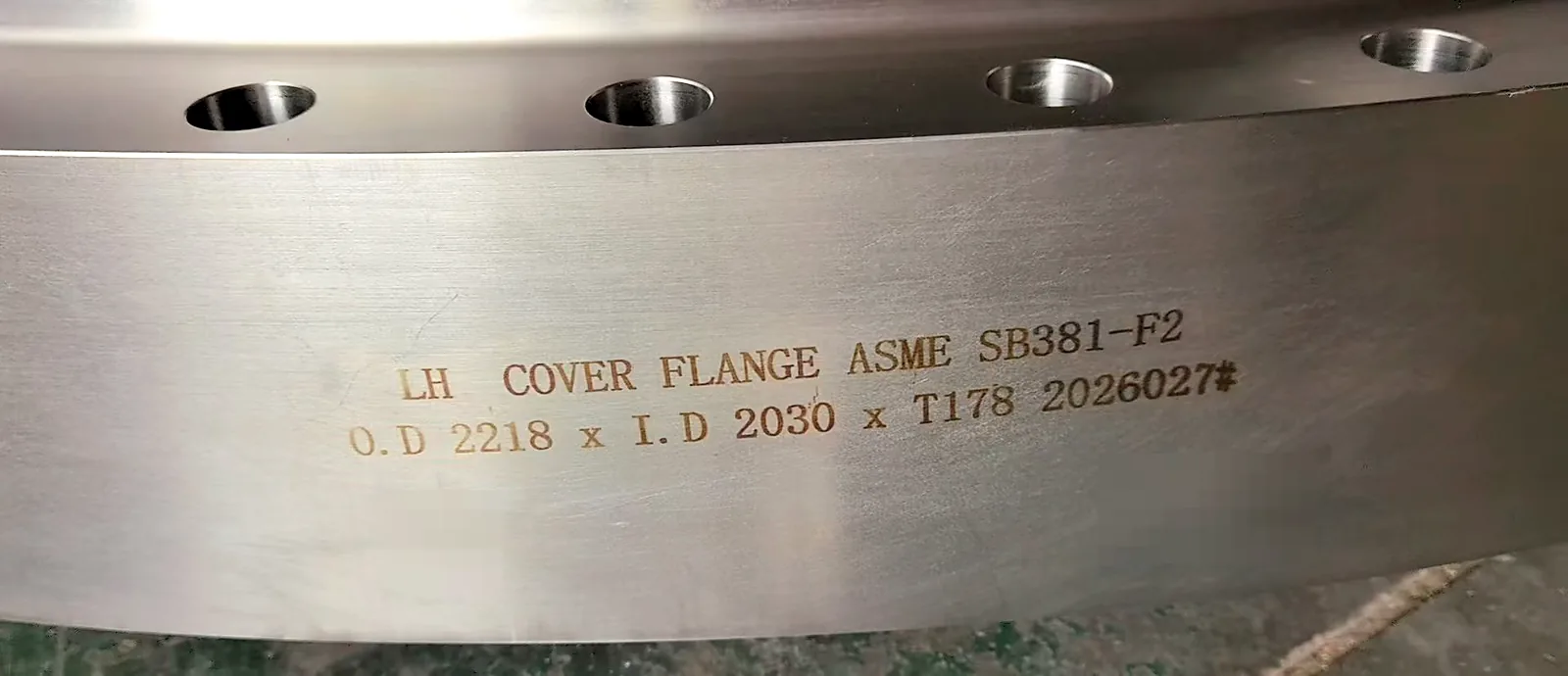 Close-up of stamped marking on titanium flange showing standard and dimensions